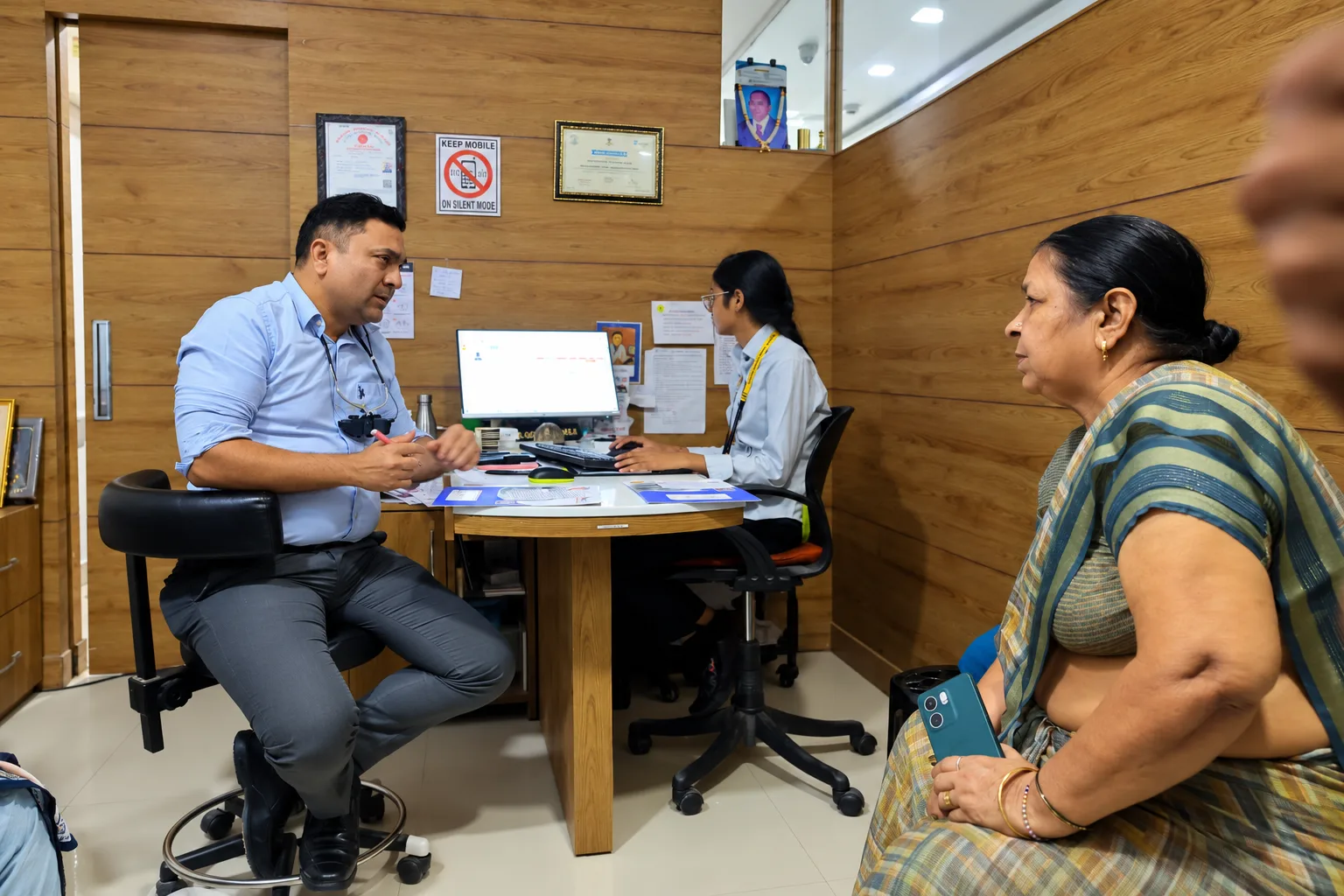 Eye doctor and clinic assistant speaking with a patient